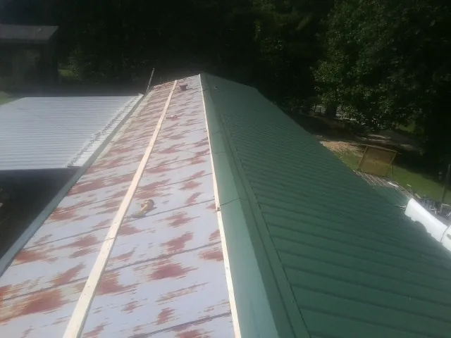 Old rusted panels beside newly installed green metal roofing — Wind Damage Roof Repair by Roofing Brothers in Johnson Creek
