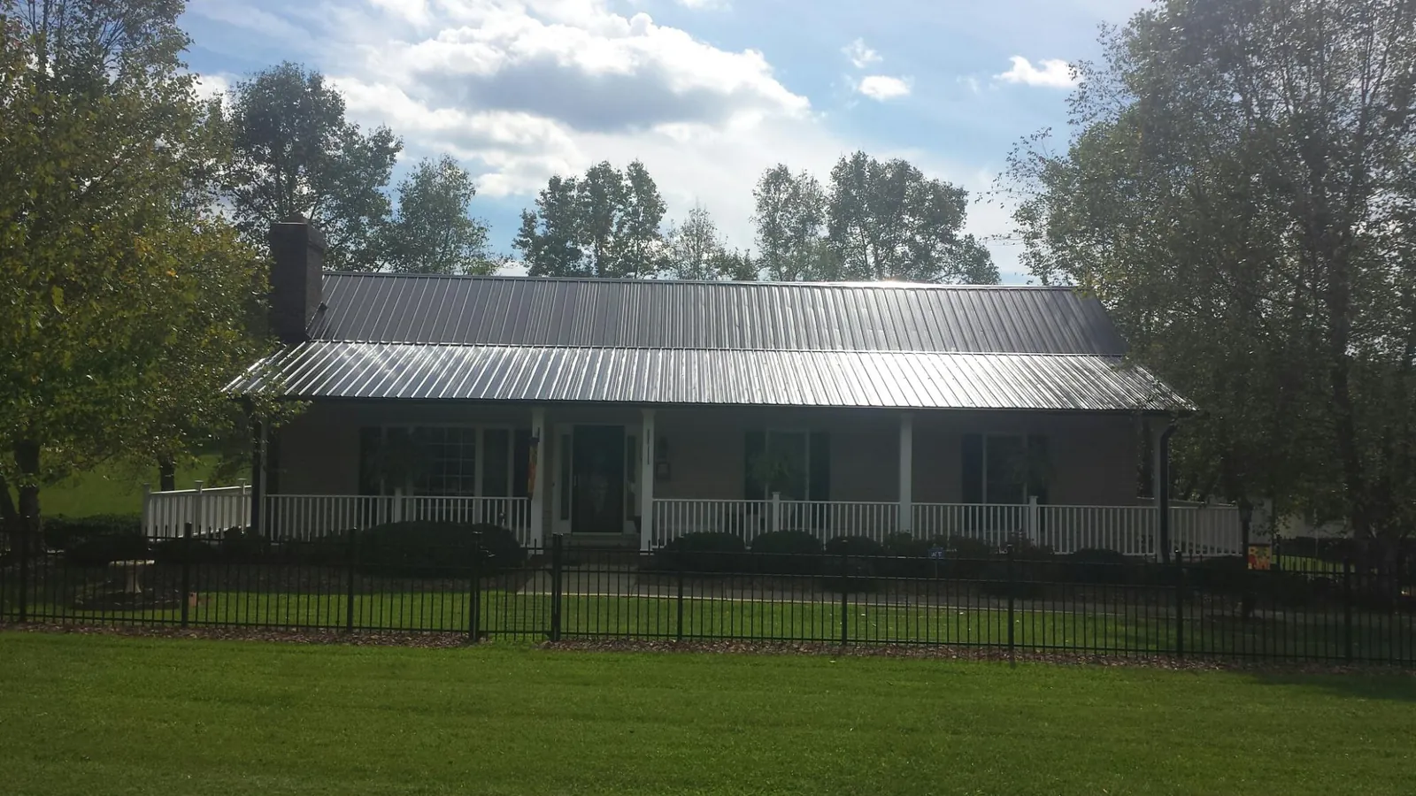 Gray metal roof on a brick ranch with a full width front porch — Gutter Guard Installation work by our crew in Johnson Creek