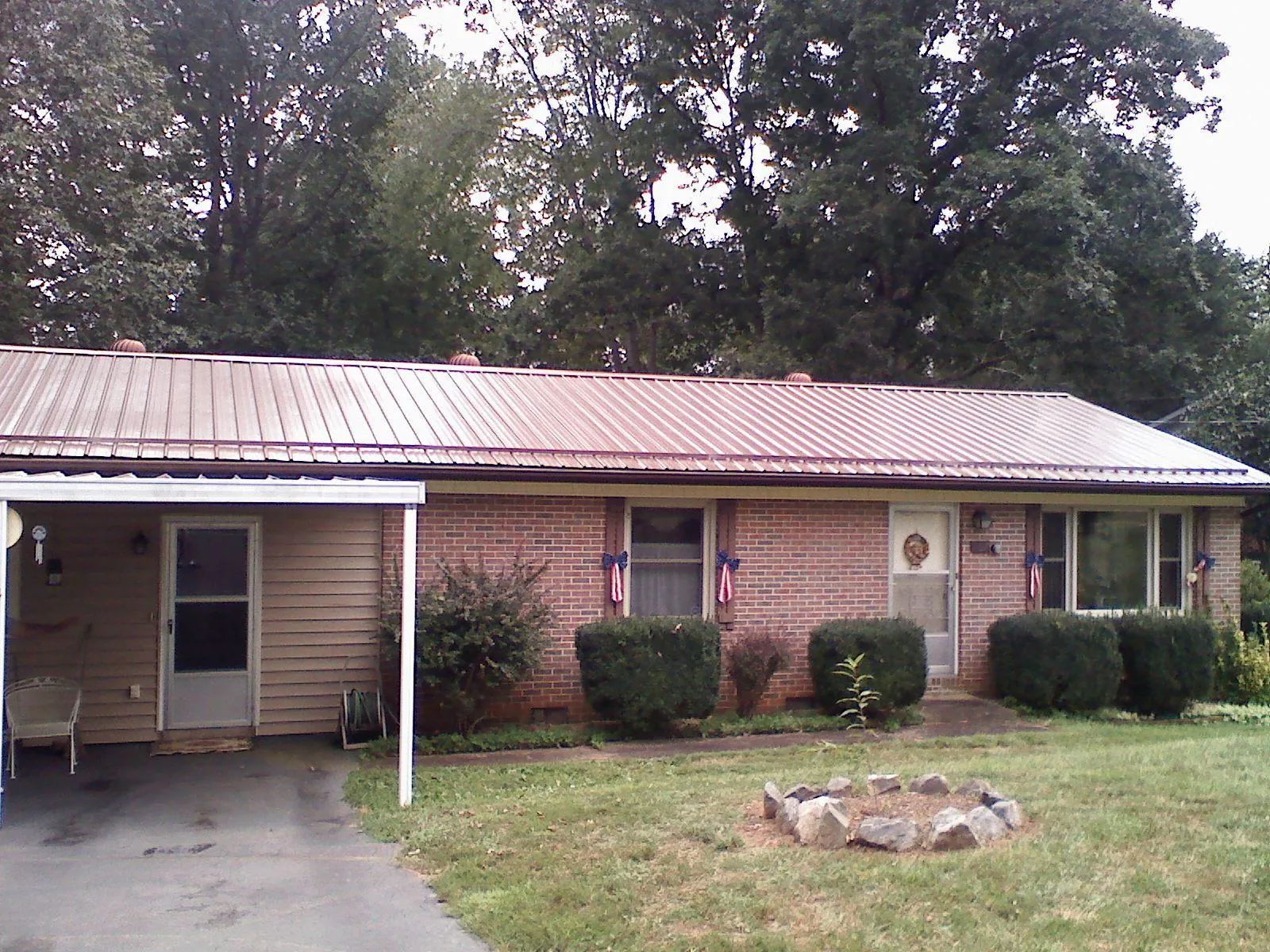 Bronze metal roof and carport on a brick ranch home — Roof Repair work by our crew in Johnson Creek