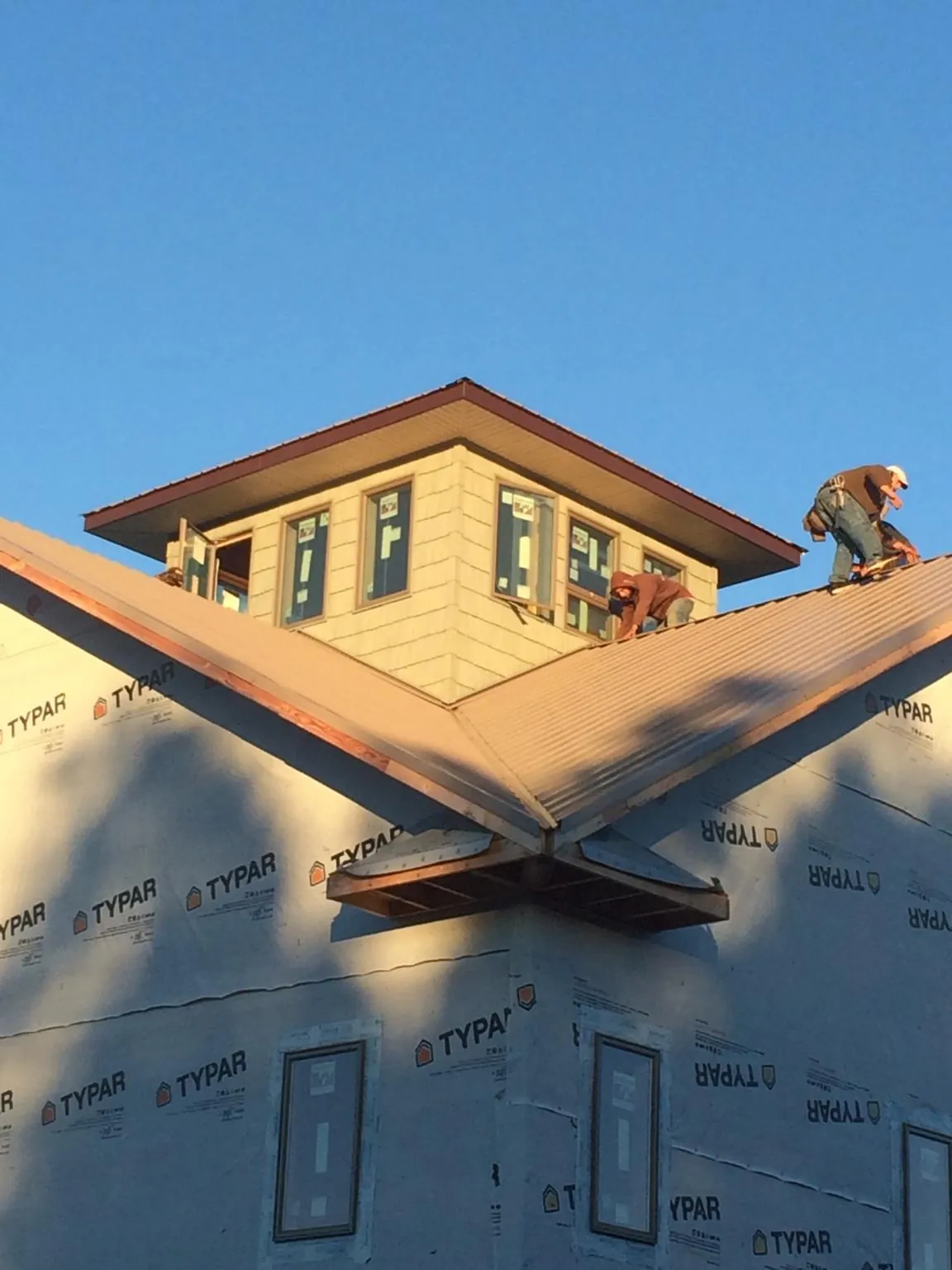 Roofers working around a rooftop cupola on a new metal roof at sunset — Roof Waterproofing in Johnson Creek by Roofing Brothers